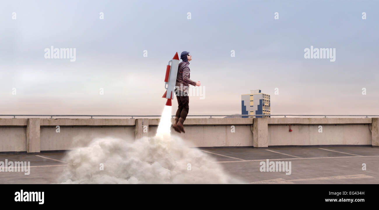 Mann von hinten oben mit Raketenrucksack aufbauend abheben Stockfoto