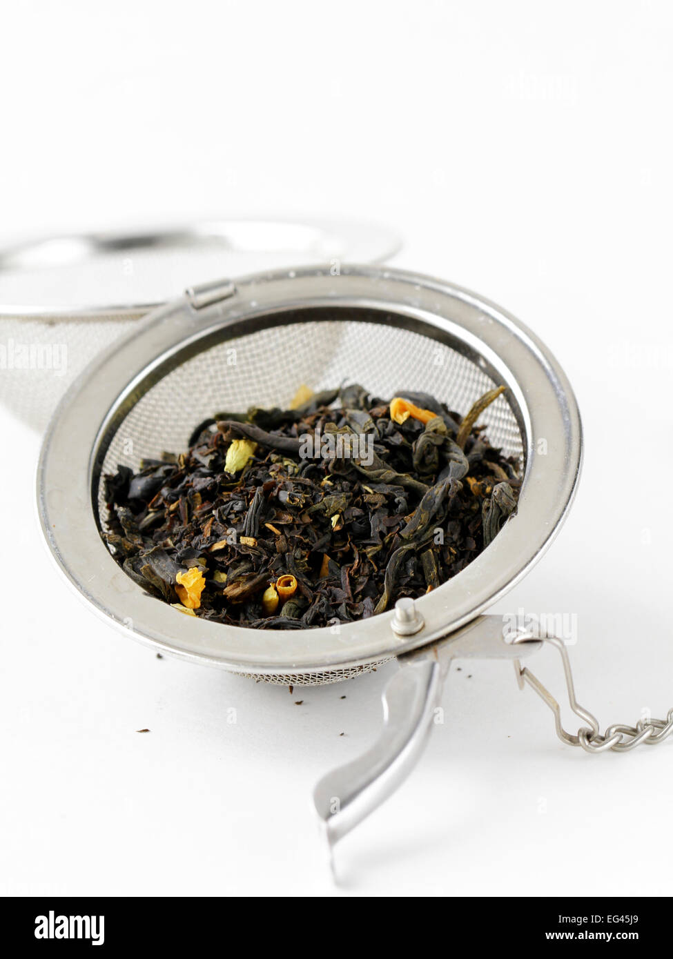 Schwarzer Blatt-Tee in einem Metallsieb auf weißem Hintergrund Stockfoto