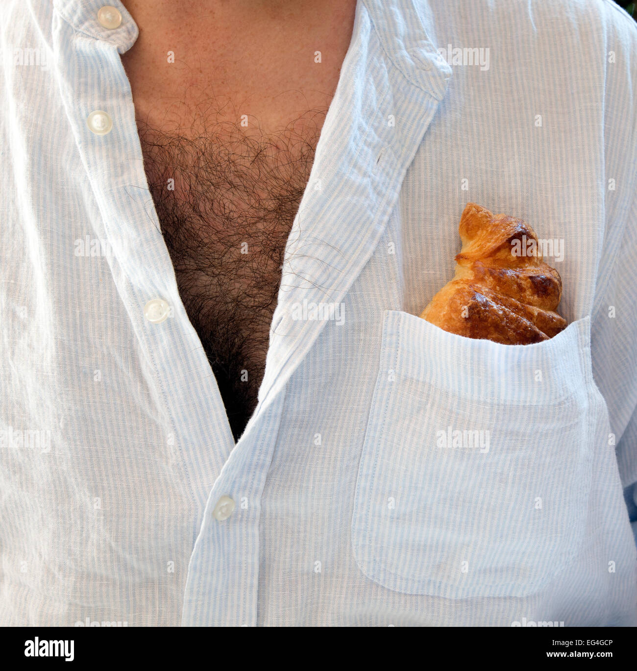 Mann mit offenen Hemd und Brust Haare und Croissant in Hemdtasche Stockfoto