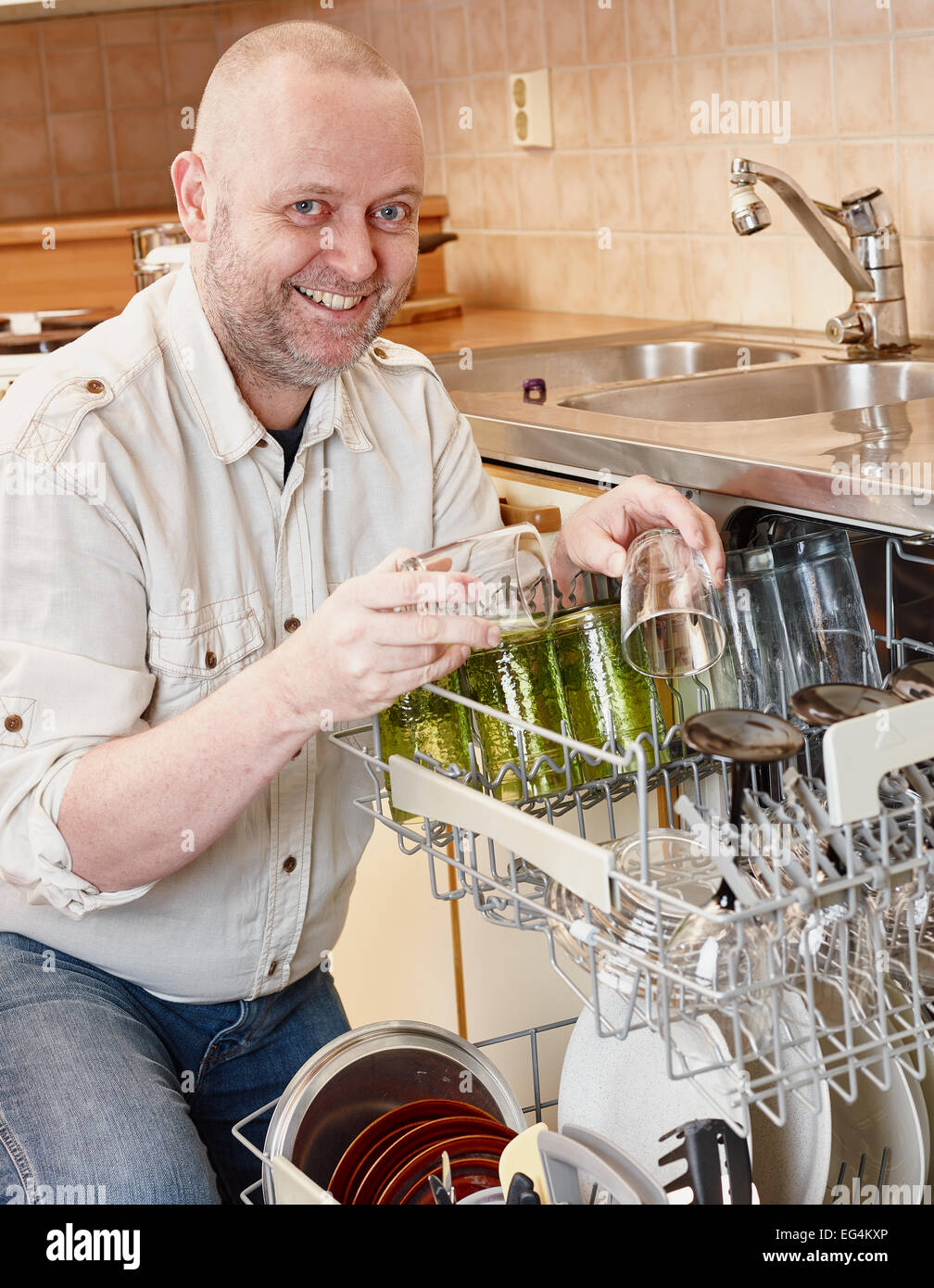 Hausübungen, lächelnd Mann um die Spülmaschine zu füllen Stockfoto