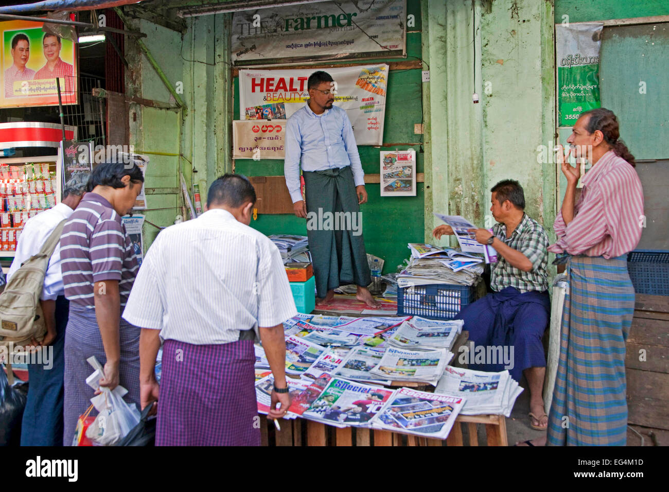 Burmesische Männer Kauf von Tageszeitungen und Zeitschriften am Straßenstand in Yangon / Rangun, ehemalige Hauptstadt von Myanmar / Birma Stockfoto