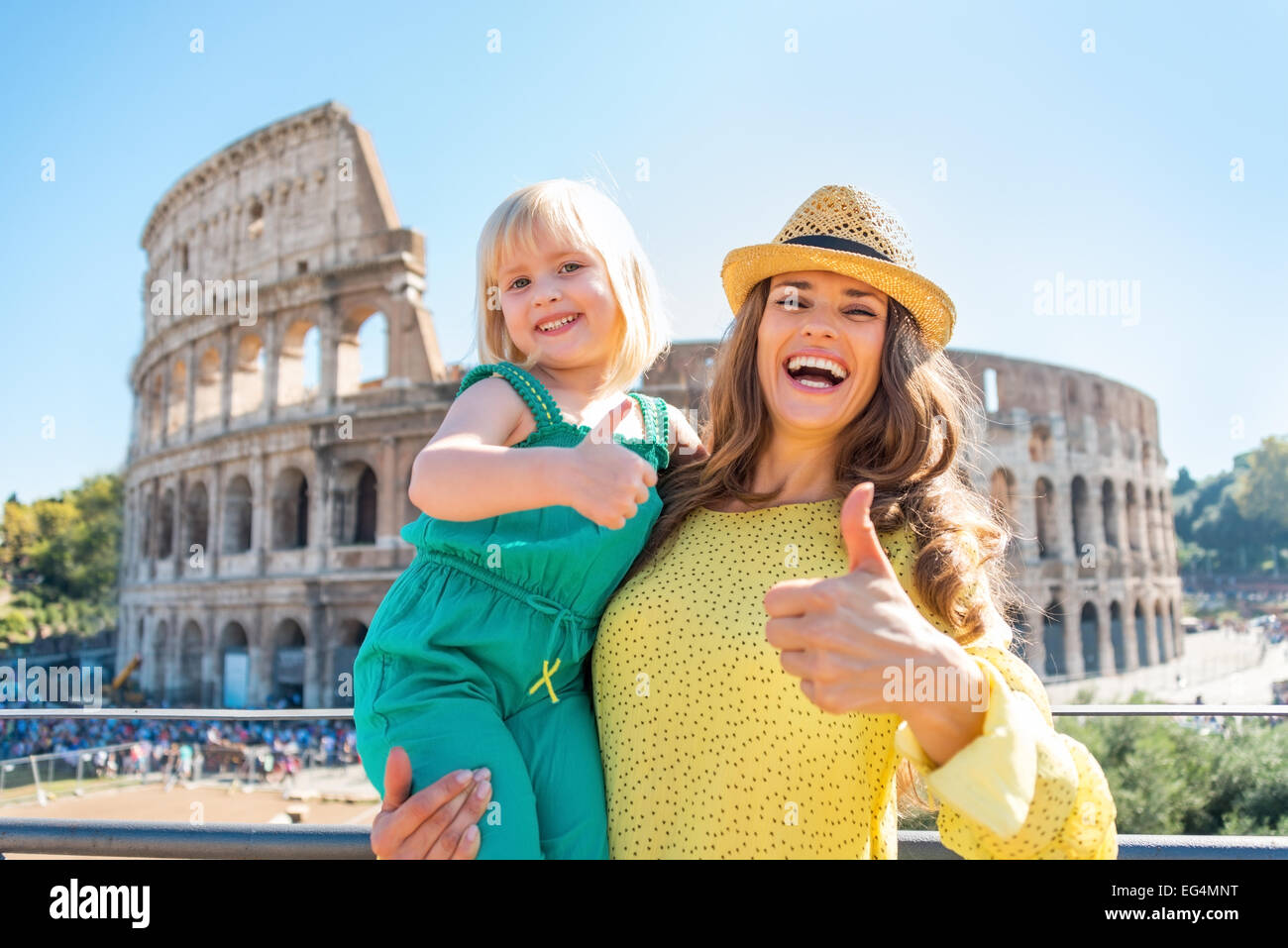 Glückliche Mutter und Baby Mädchen zeigt Daumen hoch vor dem Kolosseum in Rom, Italien Stockfoto