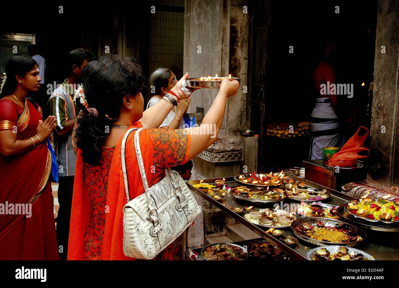 Singapur: Frau macht ein Angebot Wth eine silberne Schüssel mit Essen und Kerzen an der Sri Veeramamakaliamman Tempel Stockfoto