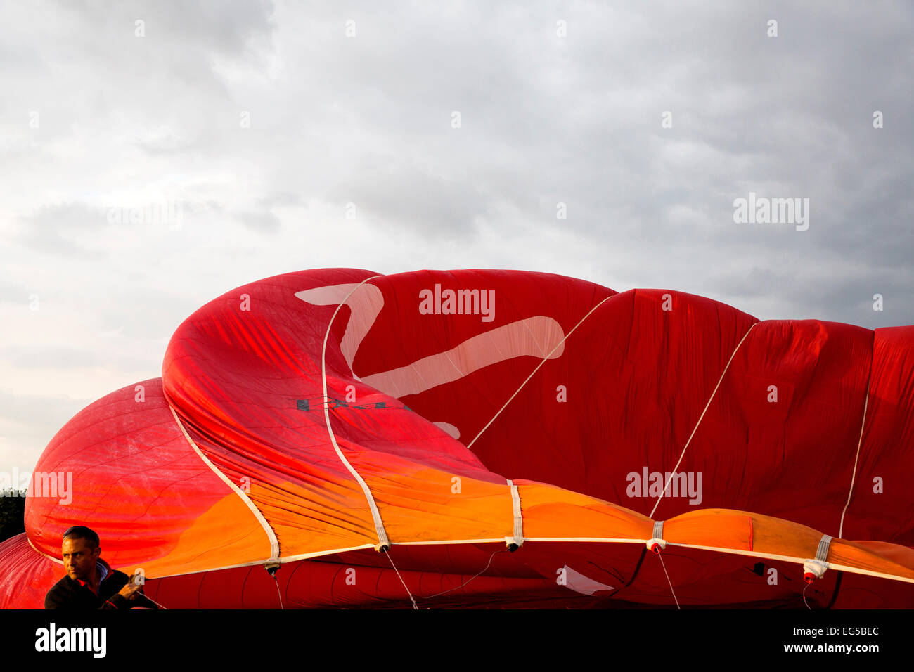 Man controlling wehenden roten Heißluftballon, South Oxfordshire, England Stockfoto