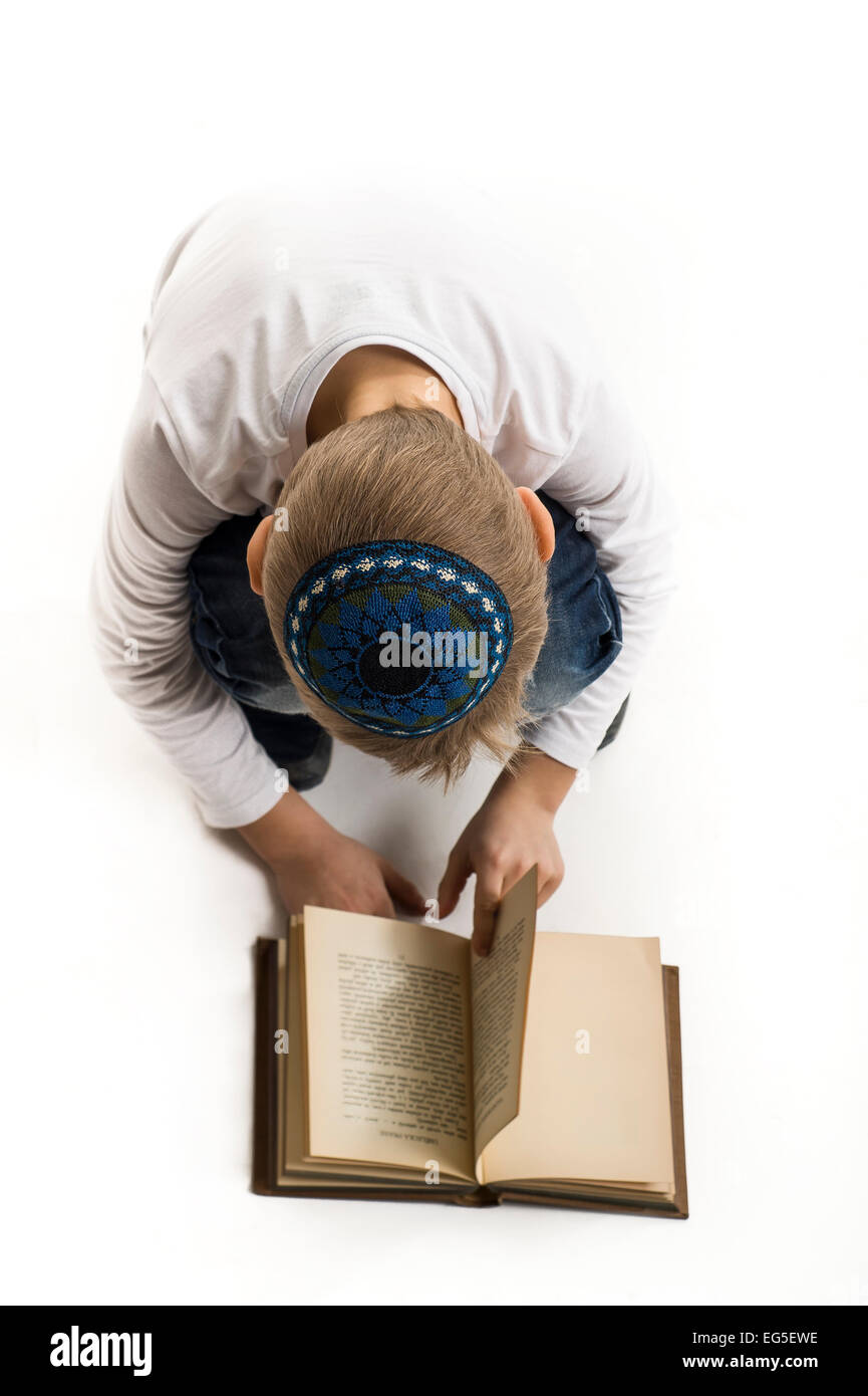 Studio-Porträt eines weißen Jungen mit jüdischen Kopfbedeckung Kipa oder Kippa und alte Bücher Stockfoto