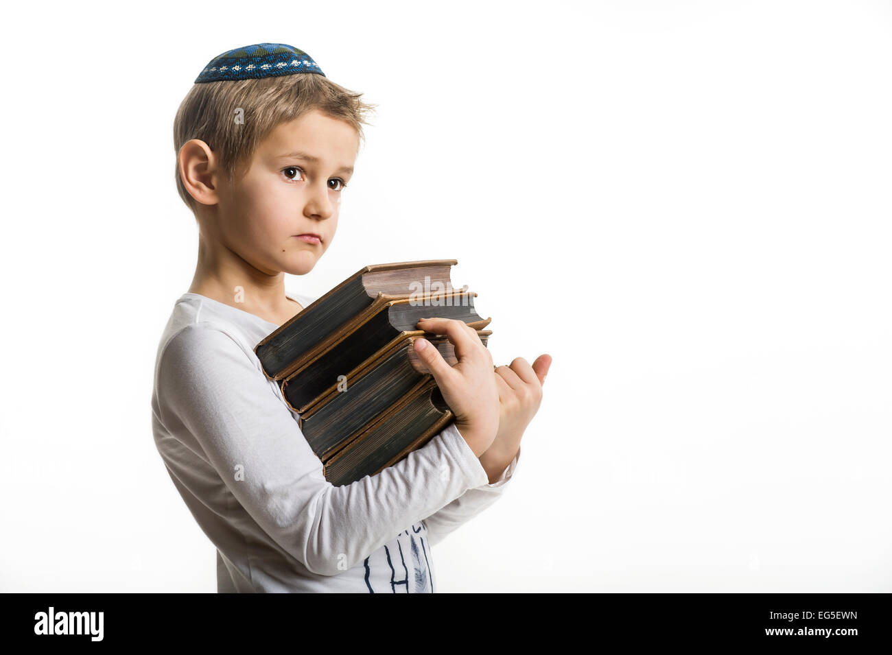 Studio-Porträt eines weißen Jungen mit jüdischen Kopfbedeckung Kipa oder Kippa und alte Bücher Stockfoto