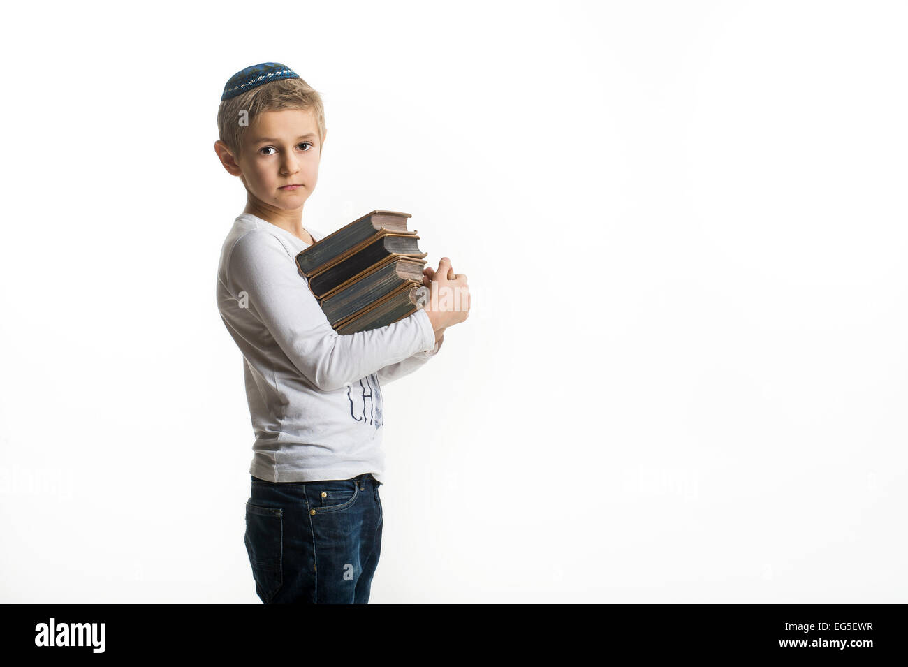 Studio-Porträt eines weißen Jungen mit jüdischen Kopfbedeckung Kipa oder Kippa und alte Bücher Stockfoto