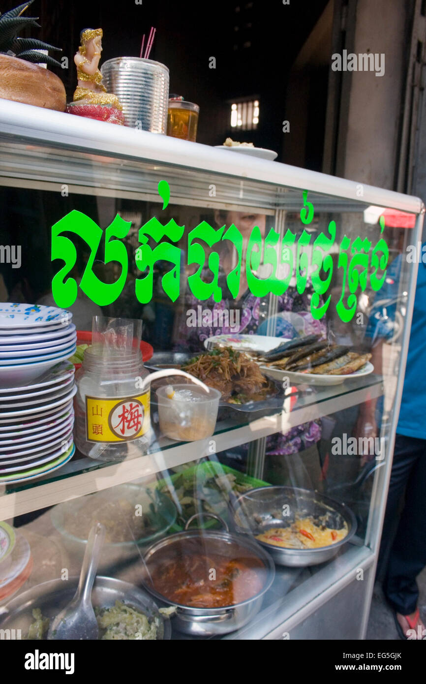 Eine Frau dient Streetfood Kunden aus einem Warenkorb in einer Gasse in Phnom Penh, Kambodscha. Stockfoto