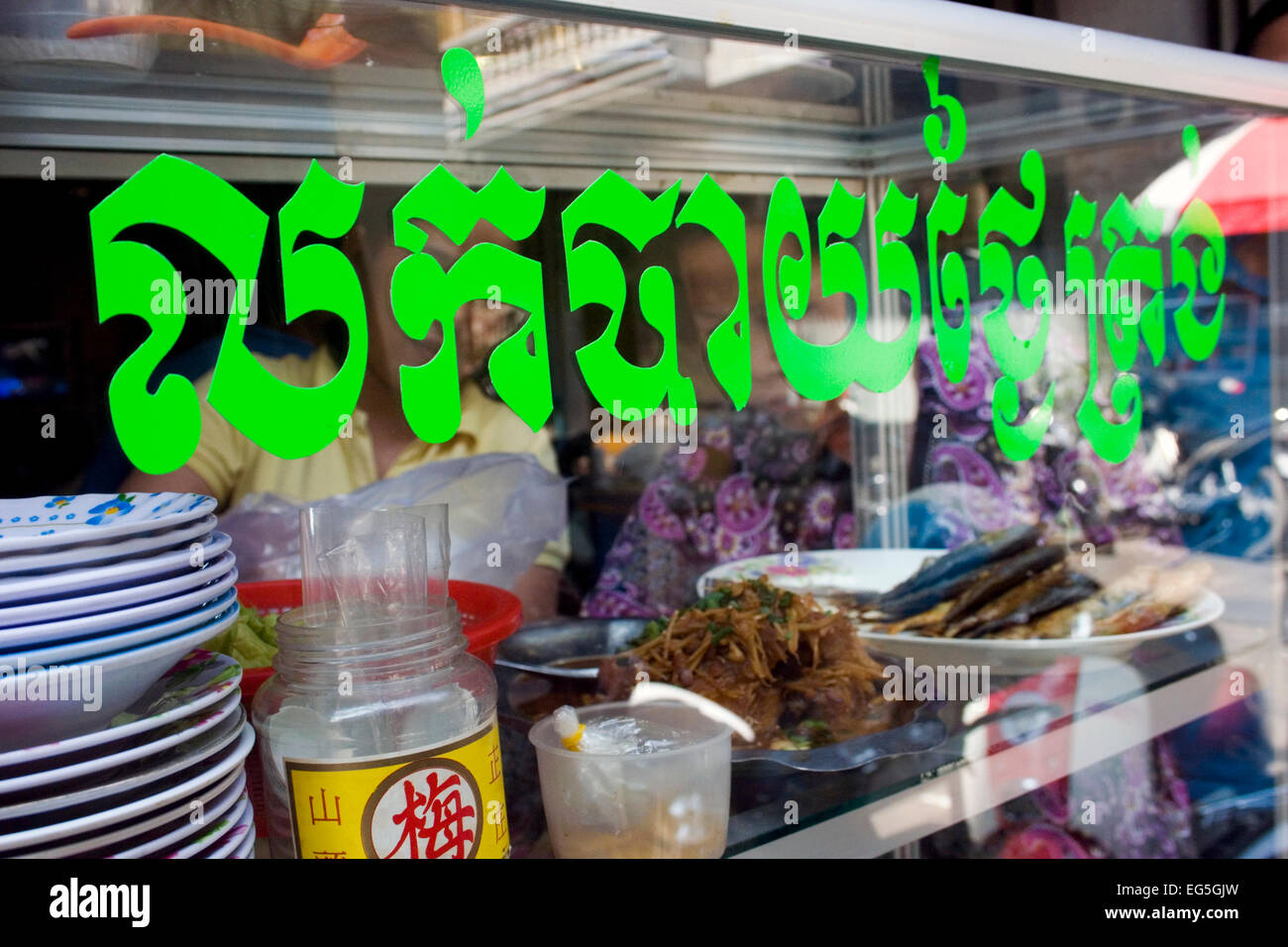 Eine Frau dient Streetfood Kunden aus einem Warenkorb in einer Gasse in Phnom Penh, Kambodscha. Stockfoto