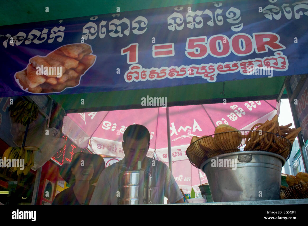 Ein Mann & Frau sind verschiedene Brot in heißem Öl kochen und servieren es als Straße Nahrung auf eine Stadt Straße in Phnom Penh, Kambodscha. Stockfoto