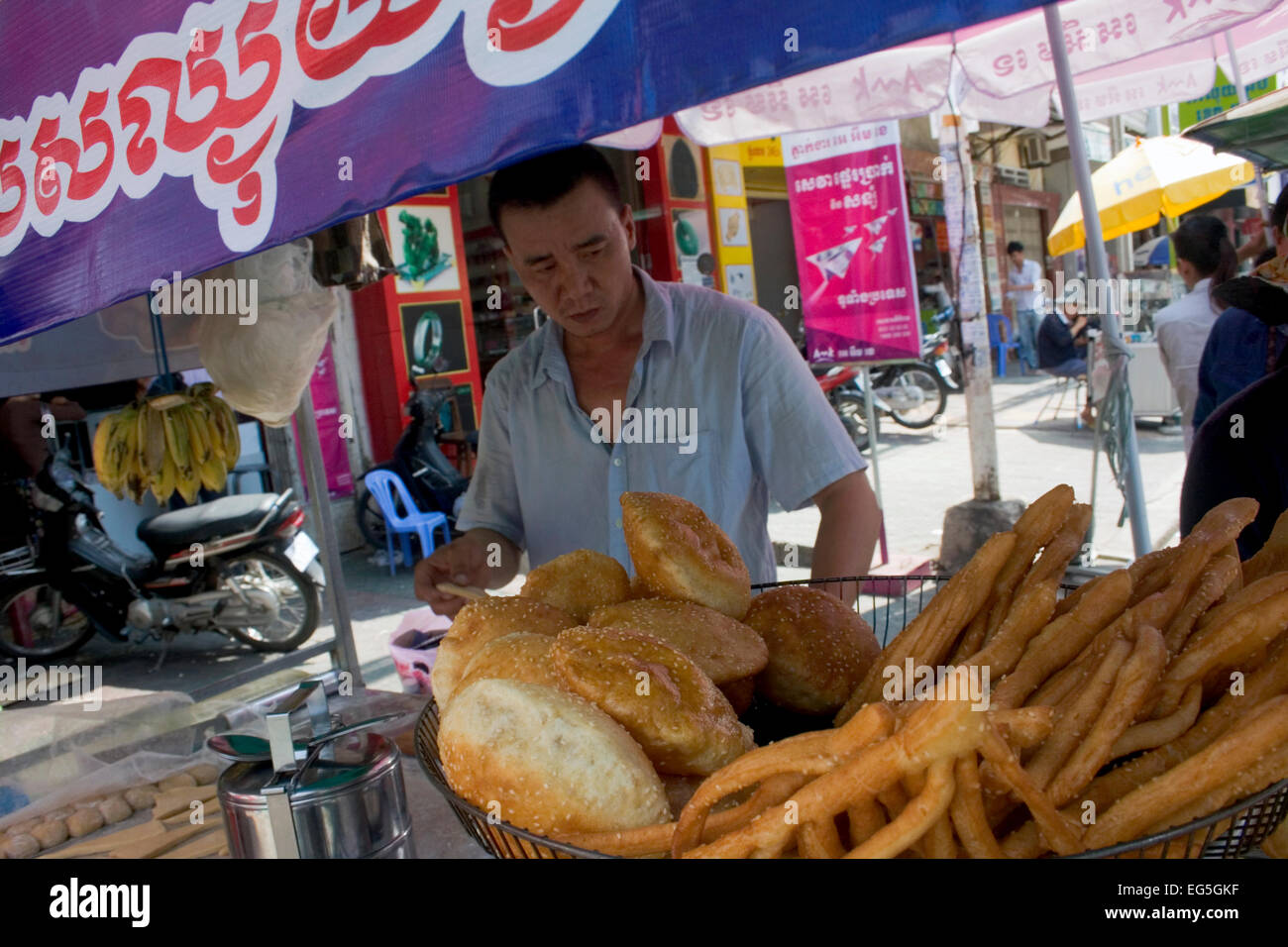 Ein Mann ist verschiedenen Brot in heißem Öl kochen und servieren es als Straße Nahrung auf eine Stadt Straße in Phnom Penh, Kambodscha. Stockfoto