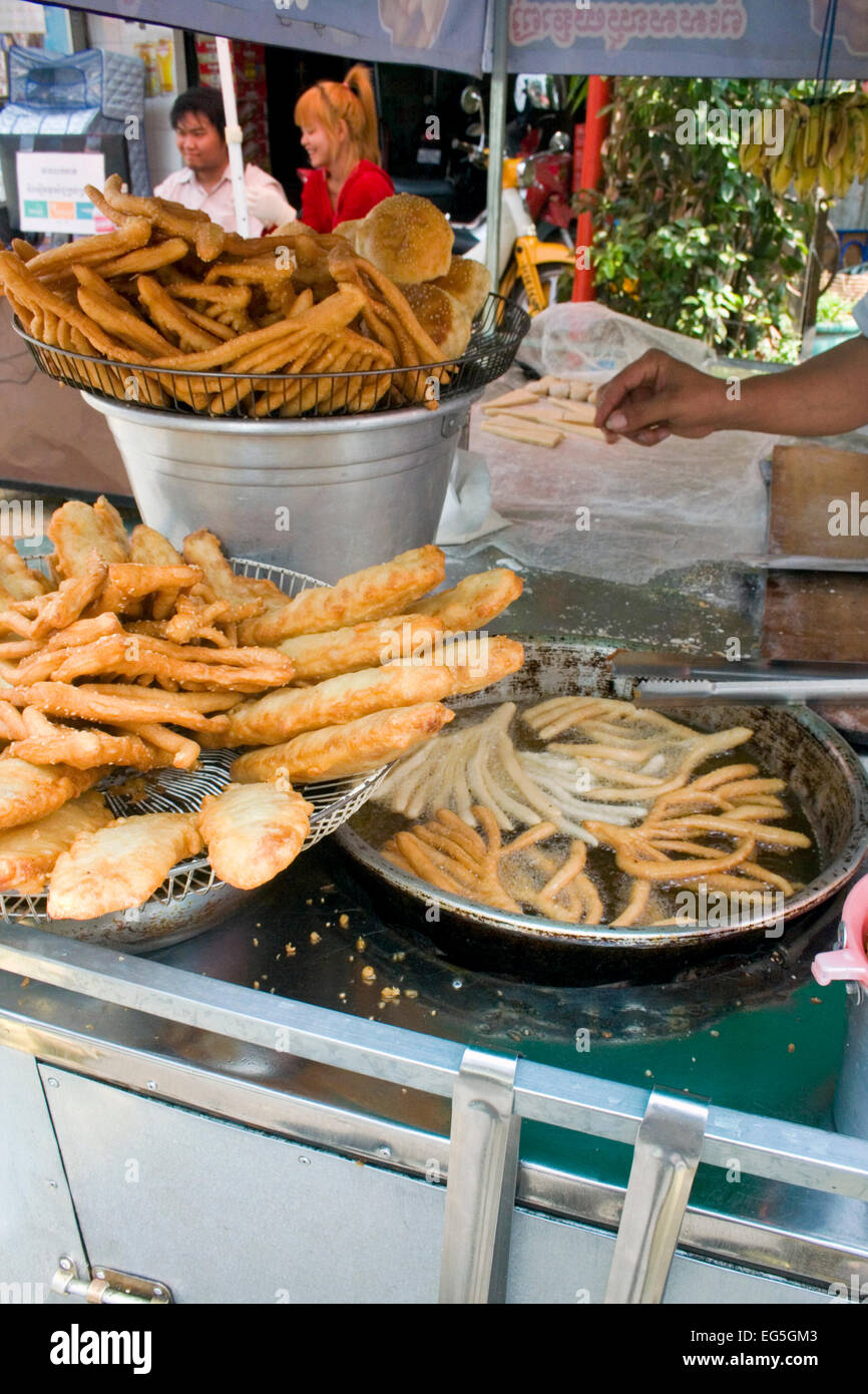 Ein Mann ist verschiedenen Brot in heißem Öl kochen und servieren es als Straße Nahrung auf eine Stadt Straße in Phnom Penh, Kambodscha. Stockfoto