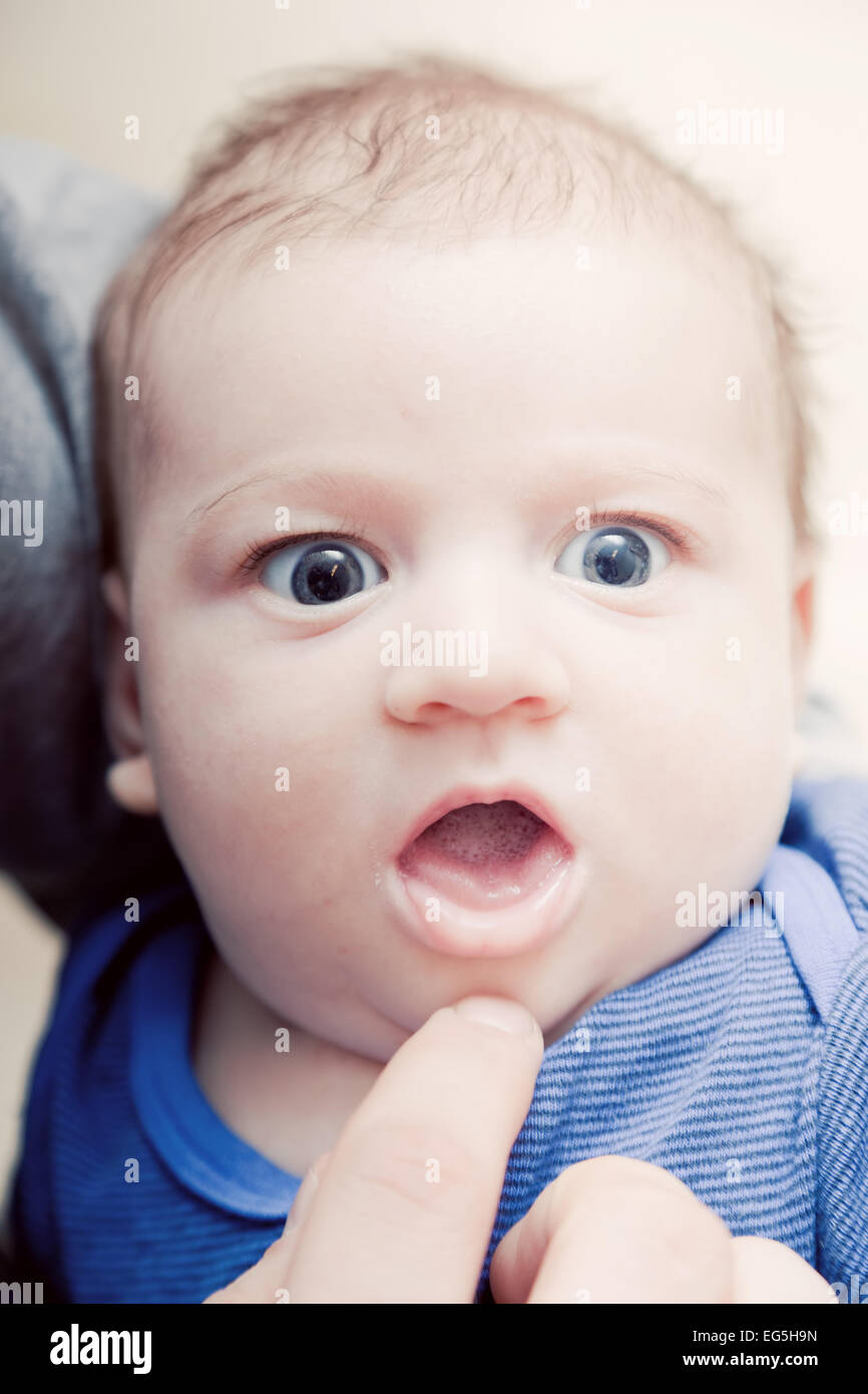 3 Monate baby wird von seinen Eltern mit einem Finger steckte. Ausdruck von Überraschung Stockfoto