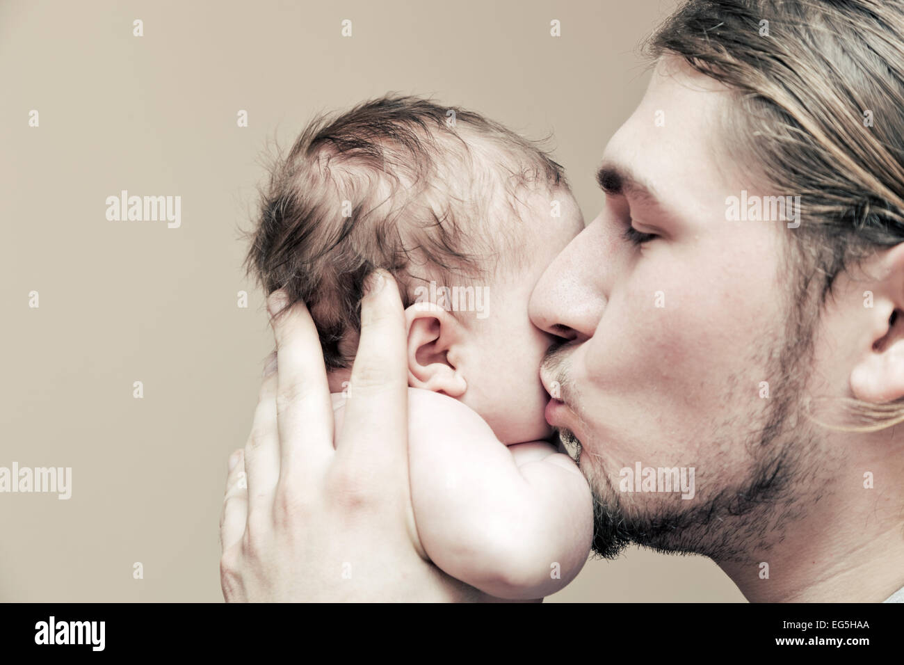 Vater mit seinem jungen Baby kuscheln und ihn auf die Wange zu küssen. Elternschaft, Liebe. Stockfoto