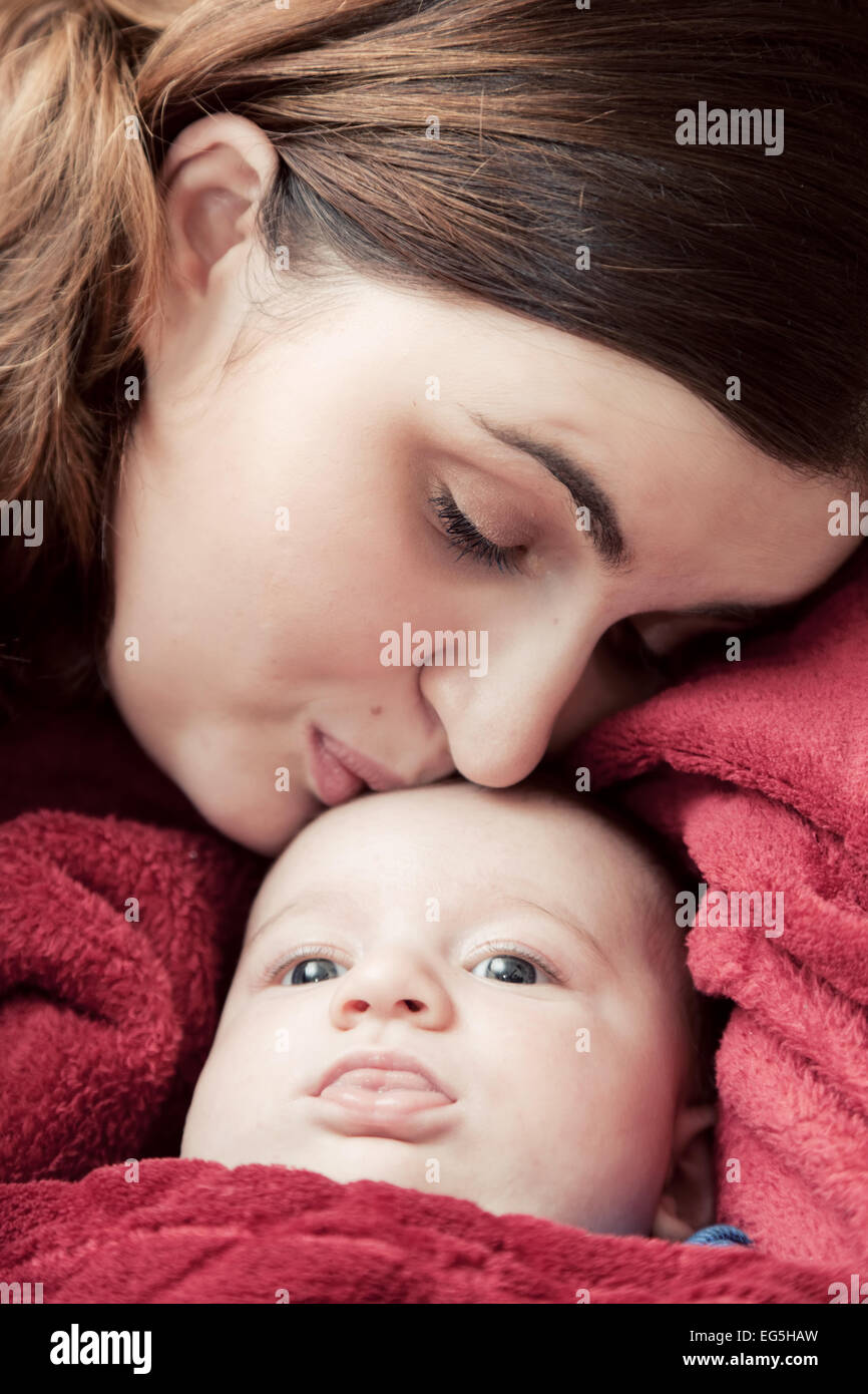Mutter mit jungen Baby kuscheln und küssen ihn auf die Stirn. Elternschaft, Liebe. Stockfoto