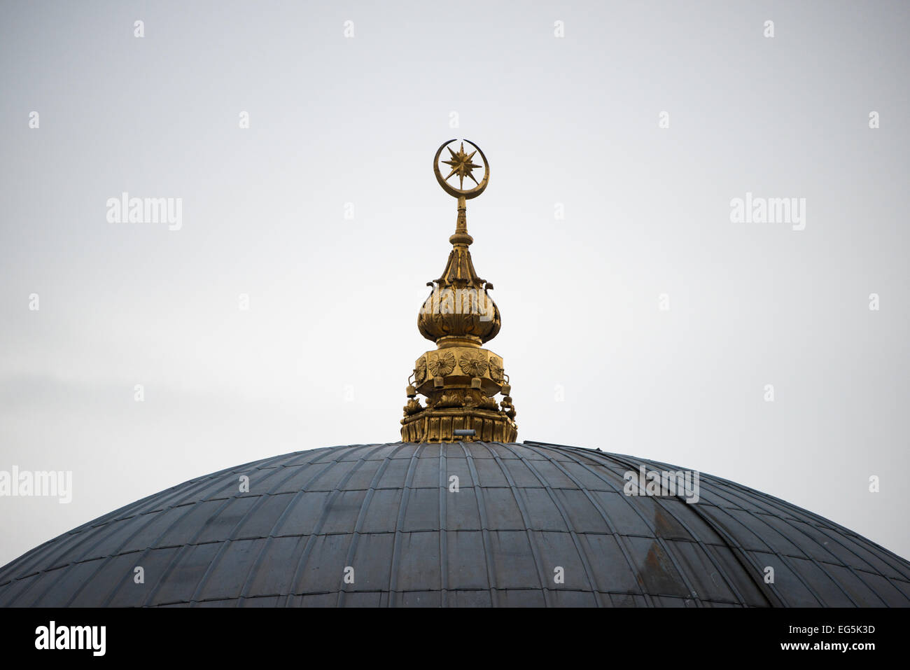 ISTANBUL, Türkei — Ein dekoratives Edelstein-Finial krönt die Kuppel der Dolmabahca-Moschee (auch bekannt als Bezmialem Valide Sultan-Moschee) entlang der Küste des Bosporus. Das kunstvoll verzierte Metall-Finial, typisch für die osmanische Moschee-Architektur, dient sowohl symbolischen als auch ästhetischen Zwecken in der islamischen Architekturtradition. Die Dolmabahce-Moschee wurde zwischen 1853 und 1855 vom armenischen Architekten Nigoğos Balyan für Bezmialem Valide Sultan, Mutter von Sultan Abdülmecid I., erbaut Stockfoto ISTANBUL, Türkei — Ein dekoratives Edelstein-Finial krönt die Kuppel der Dolmabahca-Moschee (auch bekannt als Bezmialem Valide Sultan-Moschee) entlang der Küste des Bosporus. Das kunstvoll verzierte Metall-Finial, typisch für die osmanische Moschee-Architektur, dient sowohl symbolischen als auch ästhetischen Zwecken in der islamischen Architekturtradition. Die Dolmabahce-Moschee wurde zwischen 1853 und 1855 vom armenischen Architekten Nigoğos Balyan für Bezmialem Valide Sultan, Mutter von Sultan Abdülmecid I., erbaut Stockfoto