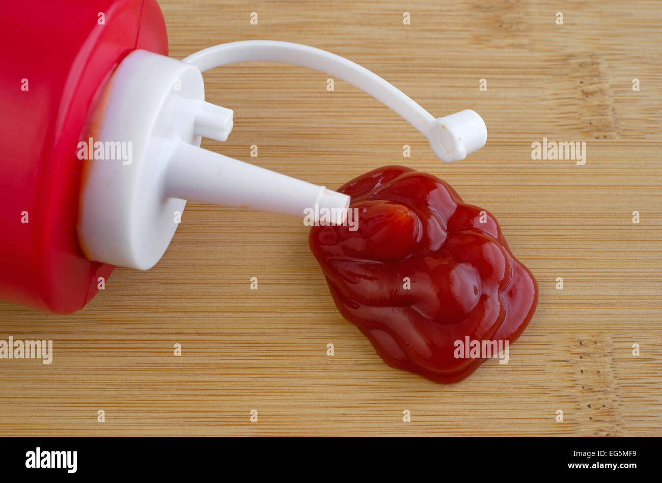Schließen Sie die Ansicht einer Flasche Ketchup auf ein Holz Schneidebrett mit einem Blob unter den Auslauf. Stockfoto