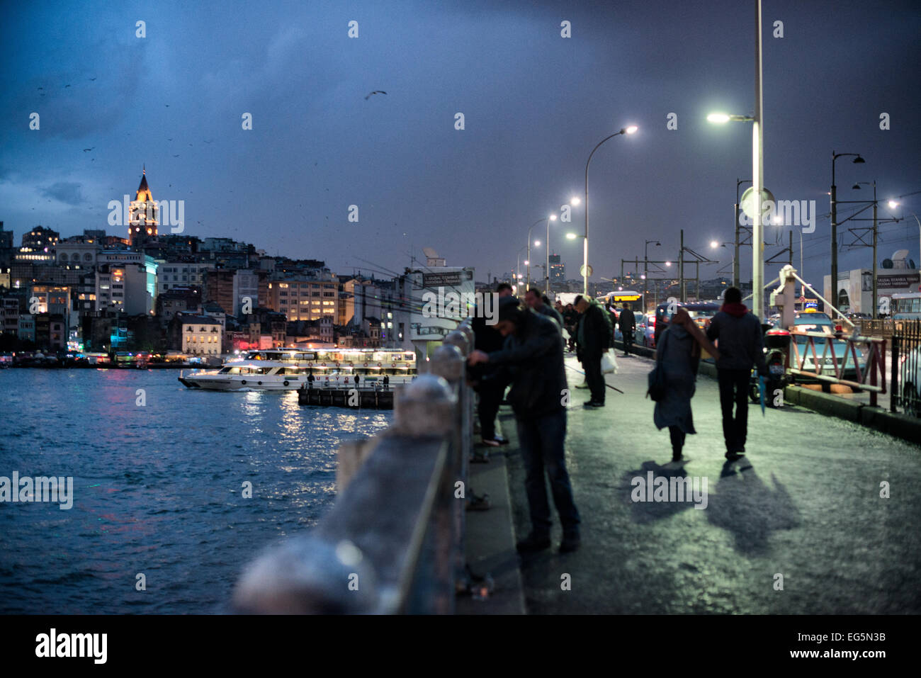 Galata Tower Galata Bridge in der Abenddämmerung Istanbul Türkei // ISTANBUL, Türkei — die historische Galata Bridge überspannt das Goldene Horn in der Abenddämmerung, wobei der beleuchtete mittelalterliche Galata Tower im Hintergrund über die Stadtlandschaft ragt. Der Turm aus dem 14. Jahrhundert ist ein markantes Wahrzeichen in der Skyline Istanbuls. Die Dämmerungsszene fängt den Übergang zwischen Tag und Nacht an zwei der bekanntesten Wahrzeichen der Stadt ein. Stockfoto