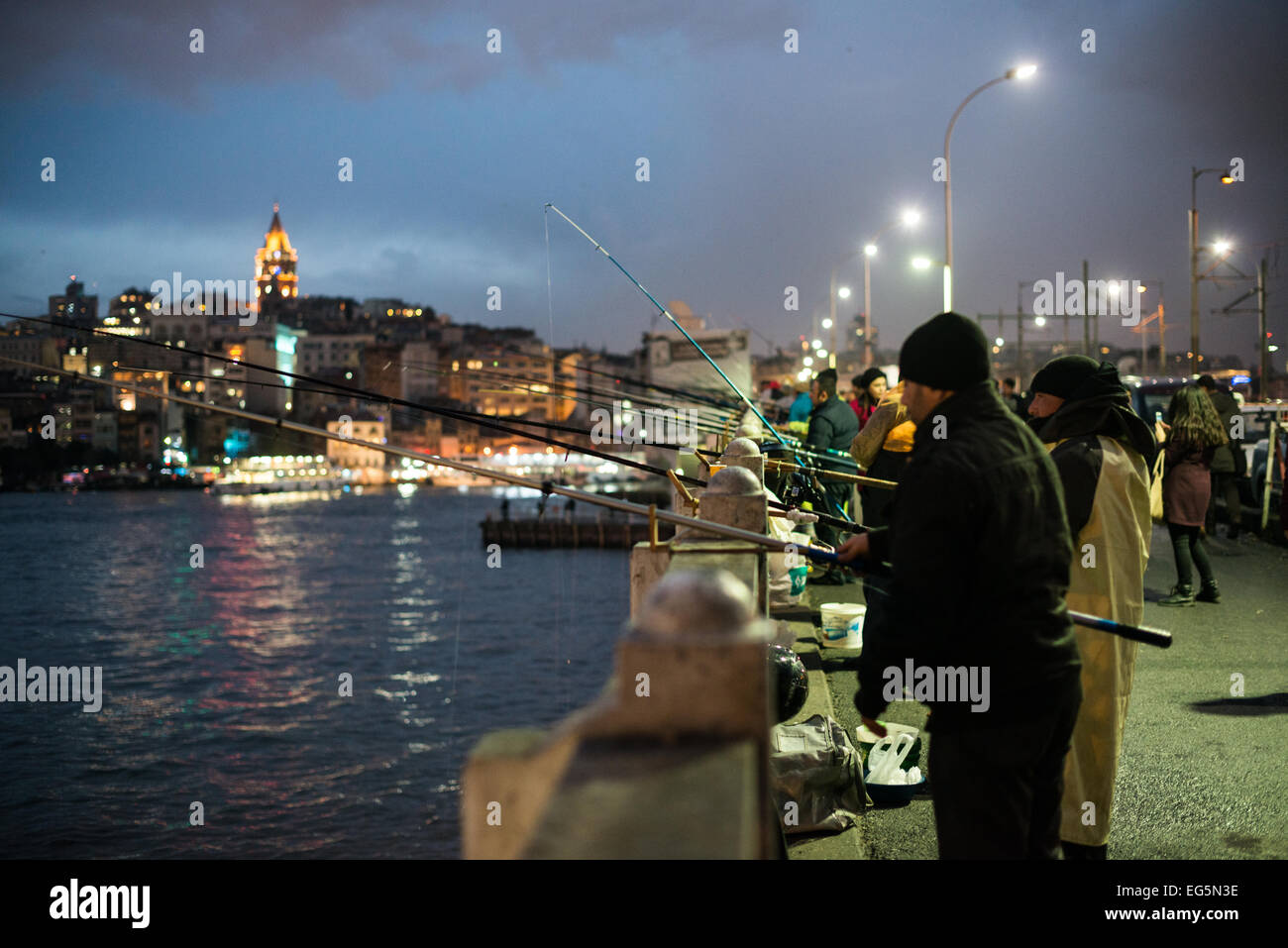 Galata-Brücke Galata-Turm Istanbul Türkei // ISTANBUL, Türkei – die historische Galata-Brücke überspannt das Goldene Horn in der Abenddämmerung, mit dem beleuchteten mittelalterlichen Galata-Turm, der sich über die Stadtlandschaft erhebt. Der Turm aus dem 14. Jahrhundert ist ein markantes Wahrzeichen in der Skyline Istanbuls. Die Dämmerungsszene fängt den Übergang zwischen Tag und Nacht an zwei der bekanntesten Wahrzeichen der Stadt ein. Stockfoto