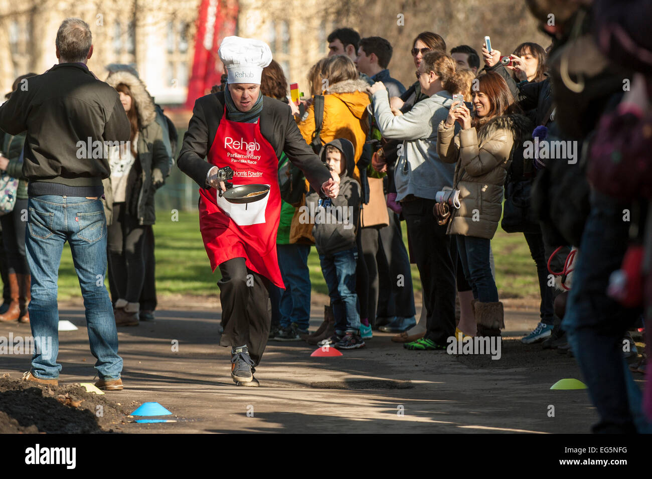 London, UK. 17. Februar 2015.   M/s, Lords und Mitglieder der parlamentarischen Pressetribüne nehmen Teil in der jährlichen, Nächstenliebe parlamentarischen Pancake Race in Victoria Tower Gardens, neben den Houses of Parliament am Faschingsdienstag.  Im Bild: Robbie Gibb, BBC täglich und Sonntag Politik nimmt Teil in das Rennen. Bildnachweis: Stephen Chung/Alamy Live-Nachrichten Stockfoto