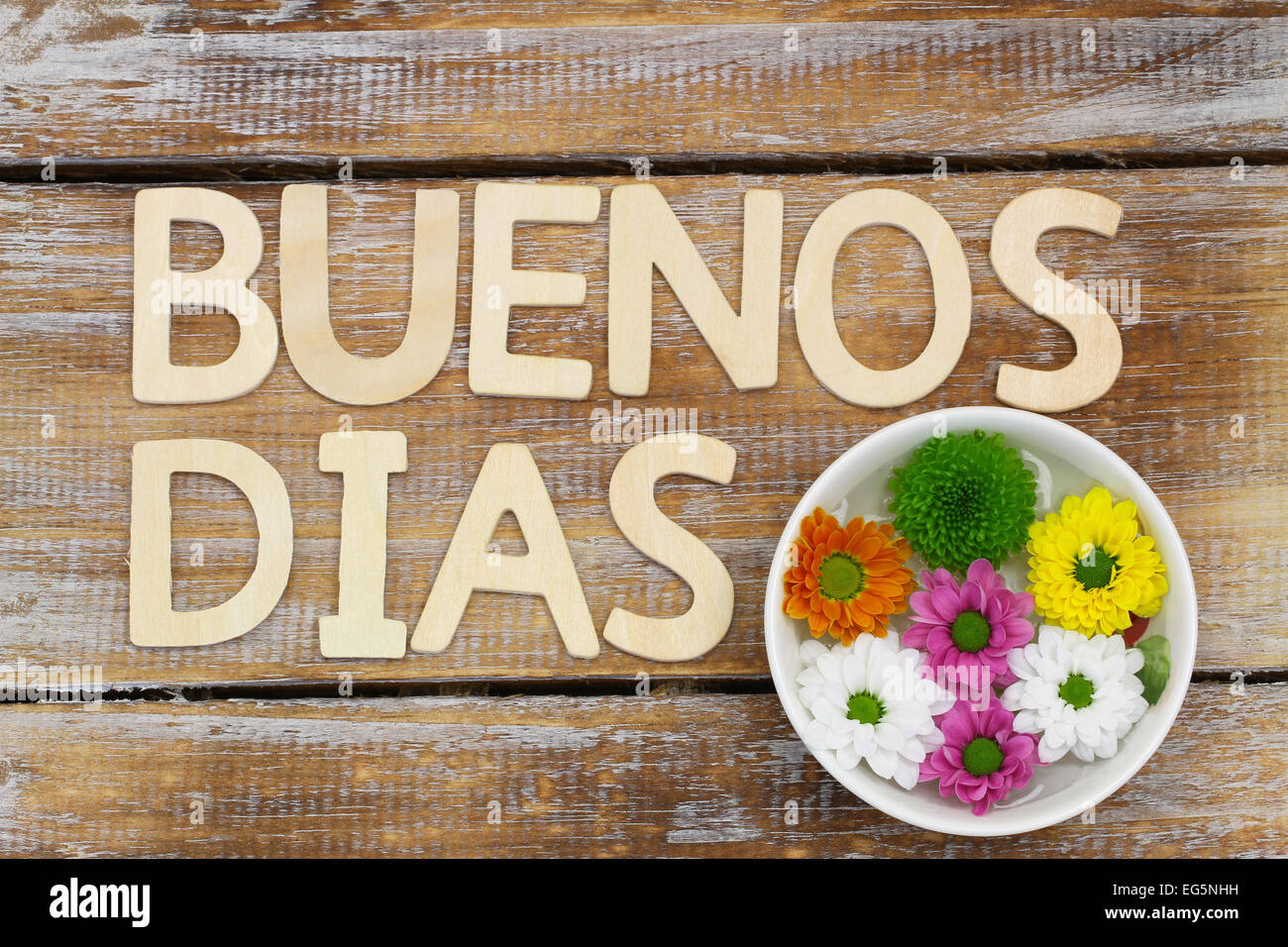 Buenos Dias (guten Morgen in spanischer Sprache) geschrieben mit Holzbuchstaben und Santini Blumen Stockfoto