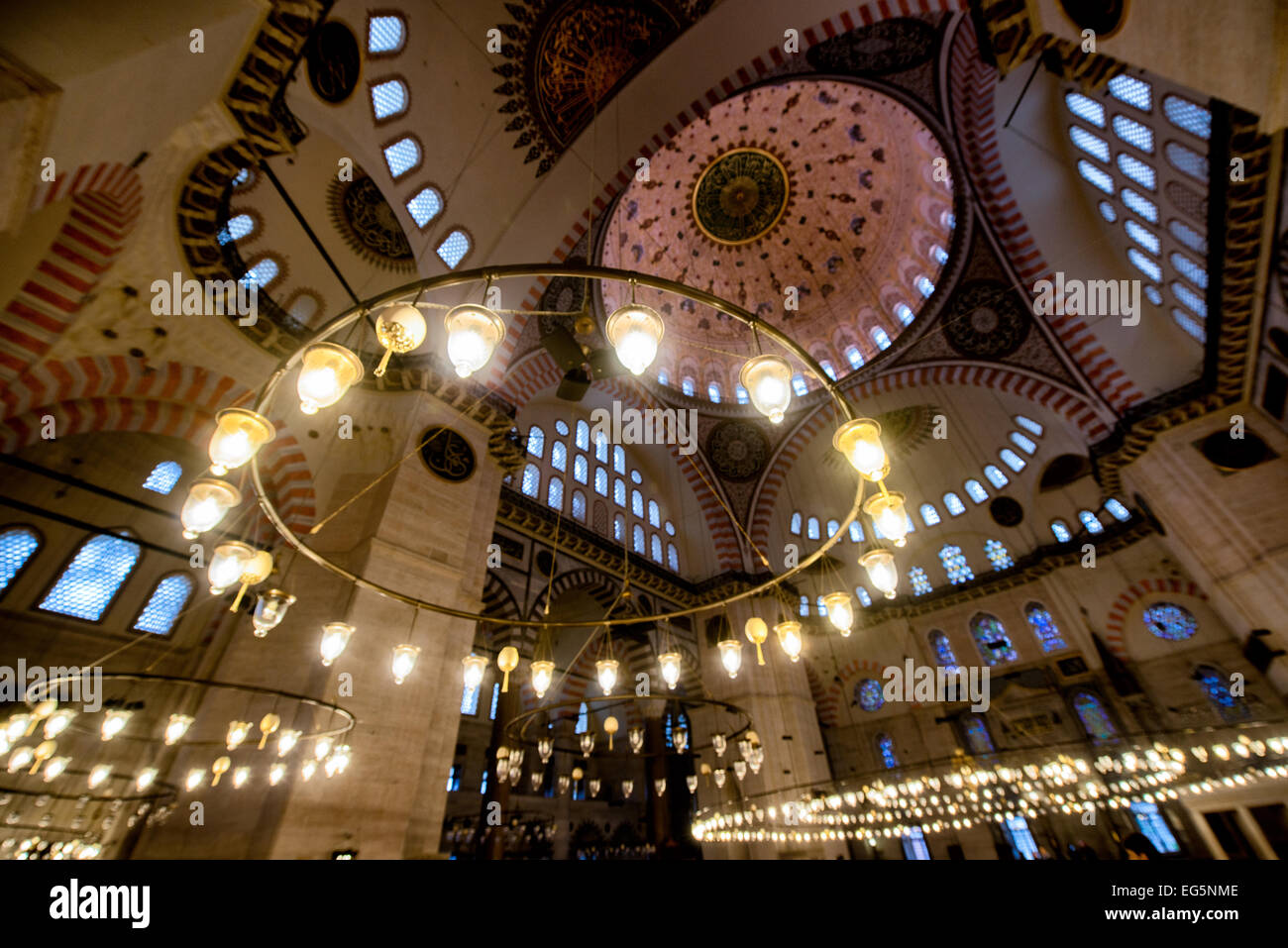 ISTANBUL, Türkei / Türkiye – im Gebetssaal der Suleymaniye-Moschee in Istanbul erleuchten markante Hängeleuchten das reich verzierte kaiserliche osmanische Innere. Der große Gebetssaal der Moschee zeigt klassische osmanische Architekturelemente und dekorative Elemente. Die Inneneinrichtung wurde 1558 fertiggestellt und veranschaulicht den raffinierten künstlerischen Stil, der während der Herrschaft Sultans entwickelt wurde. Stockfoto