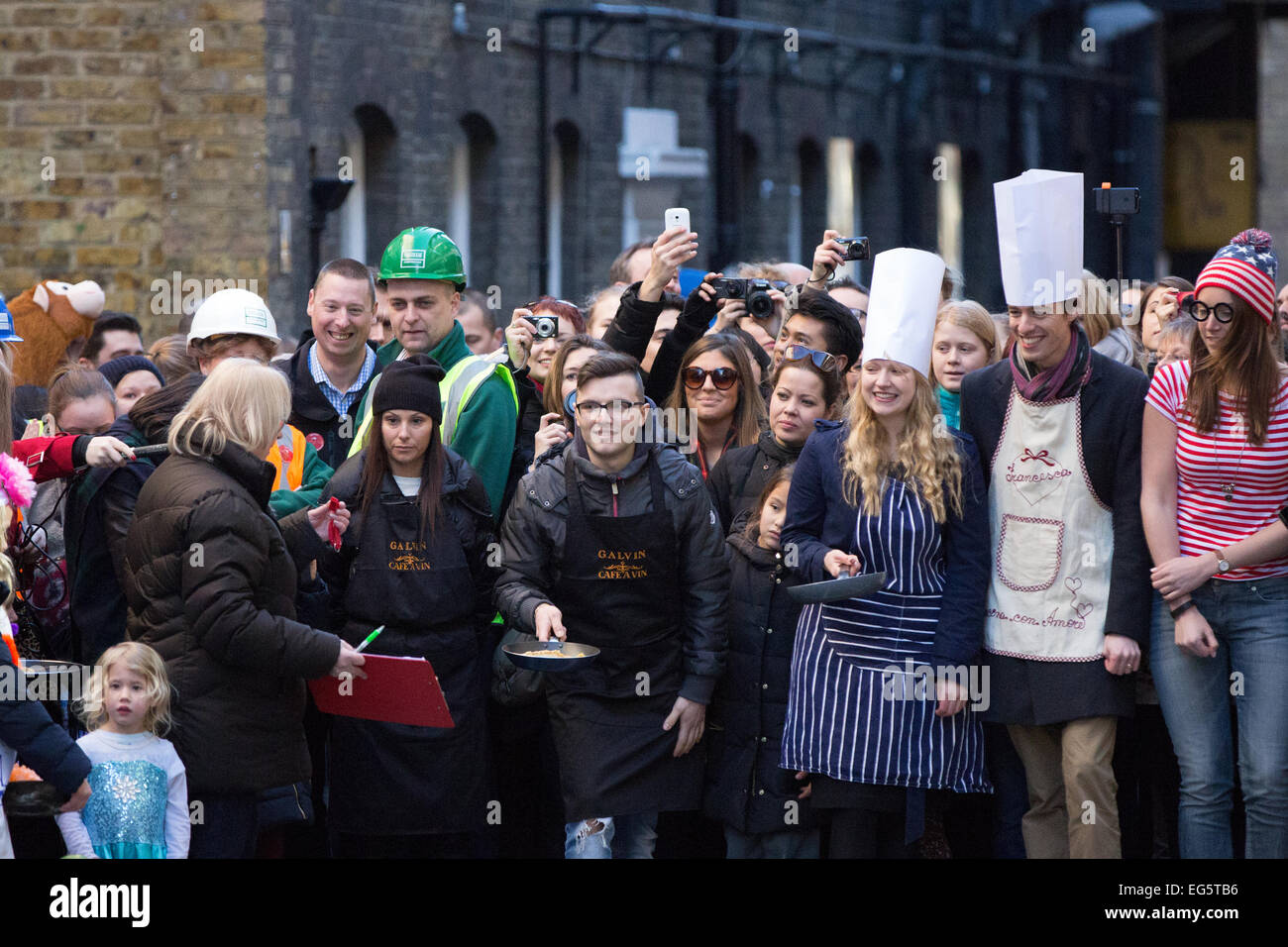 Die große Spitalfields Pancake Race 2015. Die jährliche Veranstaltung findet am Faschingsdienstag Geldbeschaffung für die London Air Ambulance basiert auf The Royal London Hospital in Whitechapel, London. Stockfoto