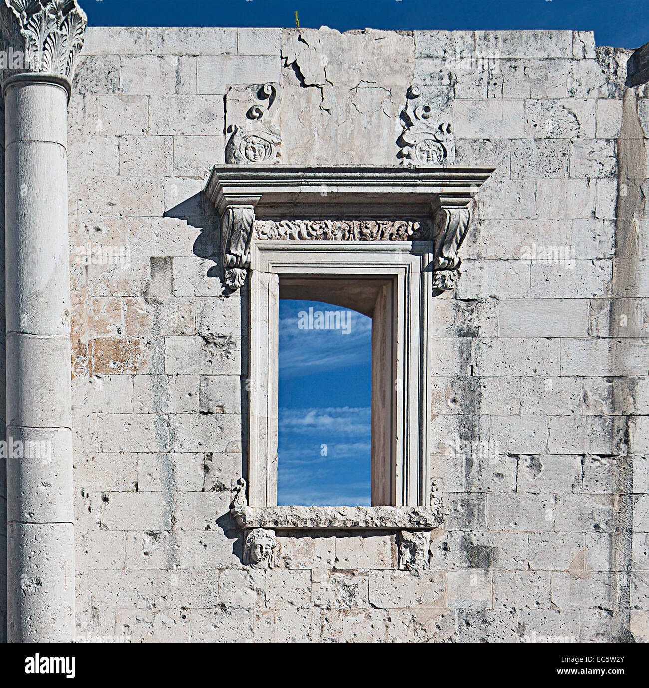 Antike römische Mauer aus weißem Stein, Säule und Fenster gegen blauen Himmel Stockfoto