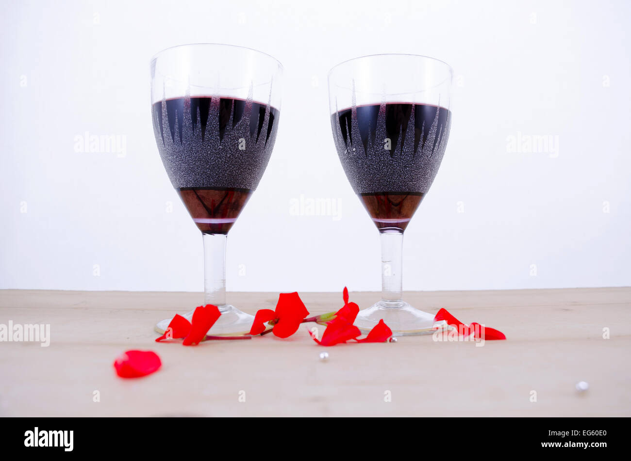 Zwei Kristallgläser Wein auf einem Tisch mit Blütenblättern Stockfoto