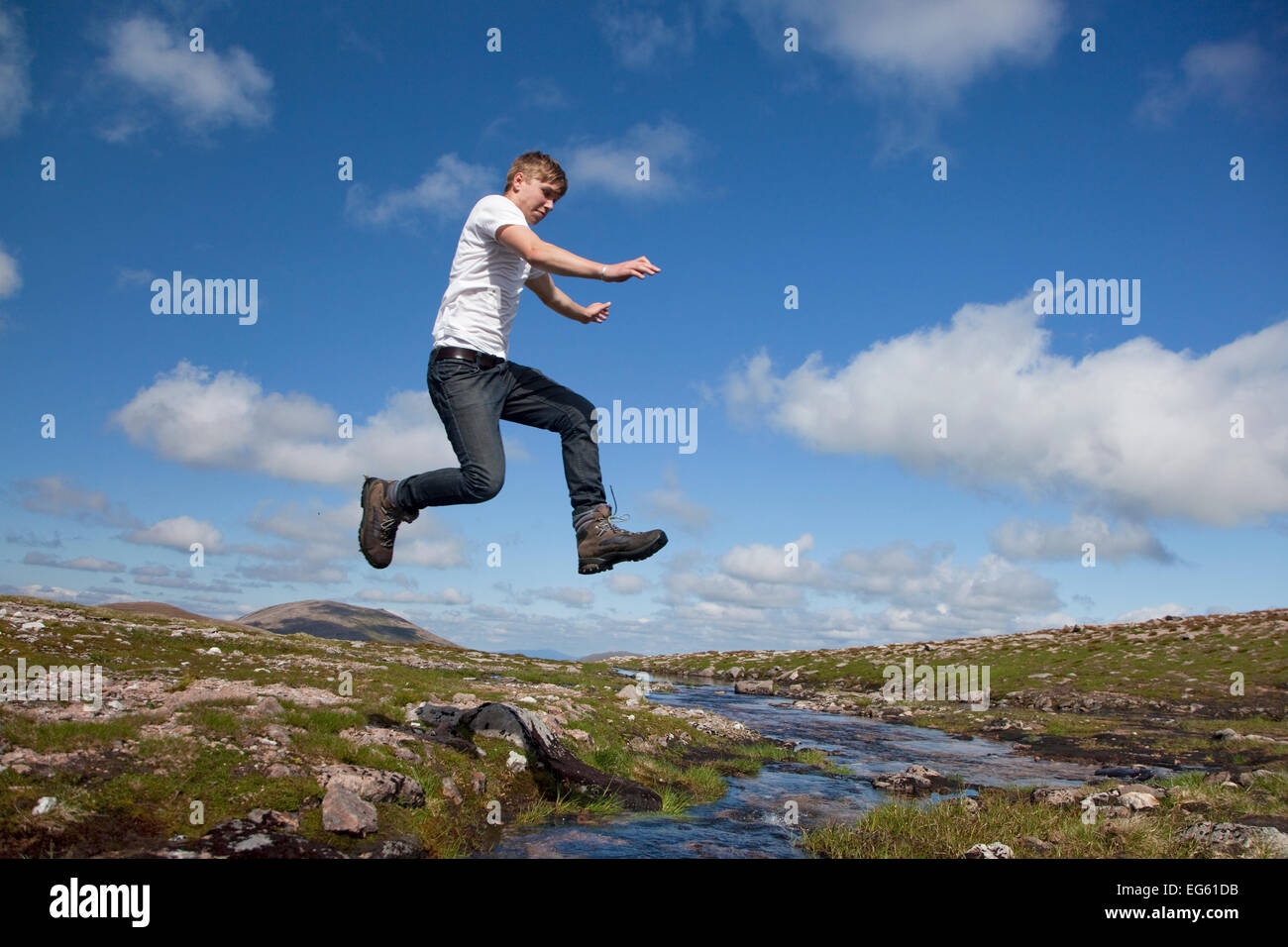 Junge (17 Jahre) springen über Hochland Bach, Cairngorms National Park, Highlands, Schottland, UK, August, Modell veröffentlicht Stockfoto