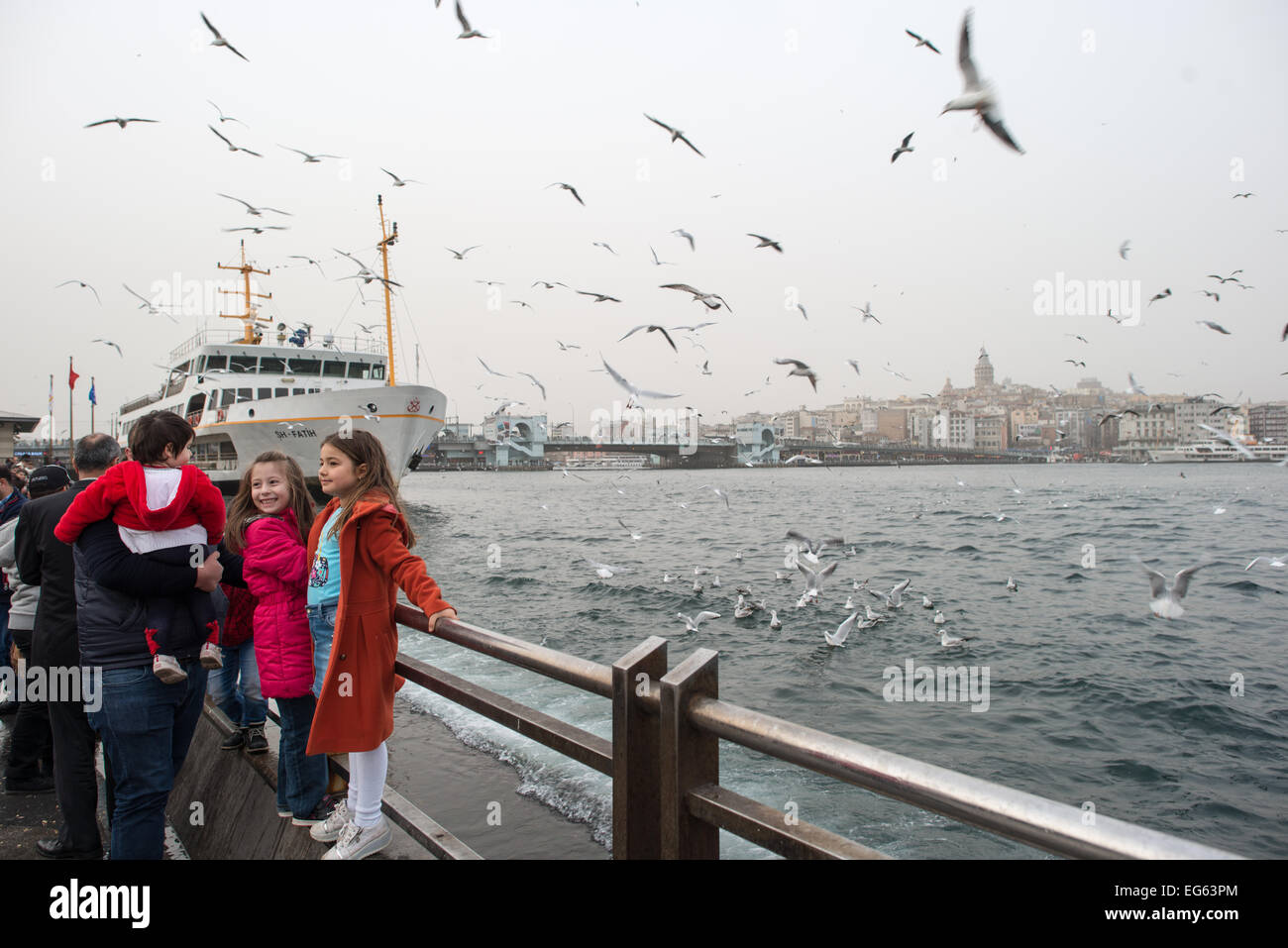 ISTANBUL, Türkei - ISTANBUL, Türkei - zwei kleine Mädchen posieren für Fotos mit den Möwen am Ufer von Eminonu in Istanbul. Im Hintergrund befindet sich der Galataturm. Eminonu ist eine historische Gegend mit einer reichen osmanischen Vergangenheit und das Herz des alten Istanbul, wo Händler und Touristen sich in einem farbenfrohen Spektakel des kulturellen Austauschs vereinen. Stockfoto