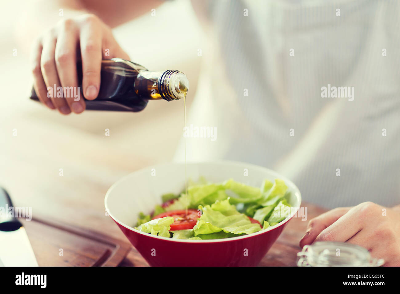 Nahaufnahme von männlichen Händen Aromatisieren von Salat in eine Schüssel geben Stockfoto