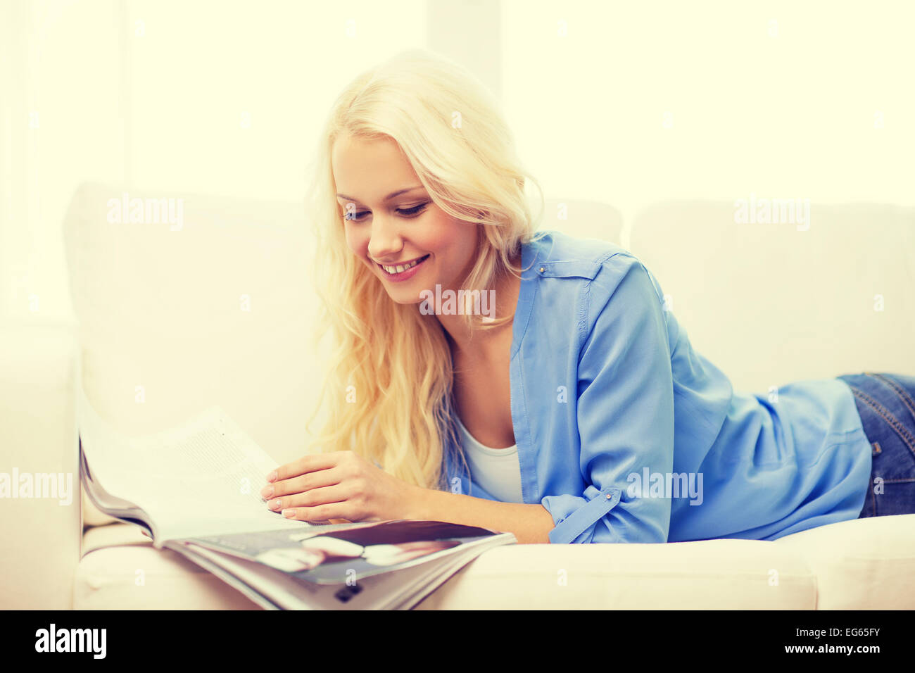 Frau auf Couch liegen und lesen zu Hause Magazin Stockfoto