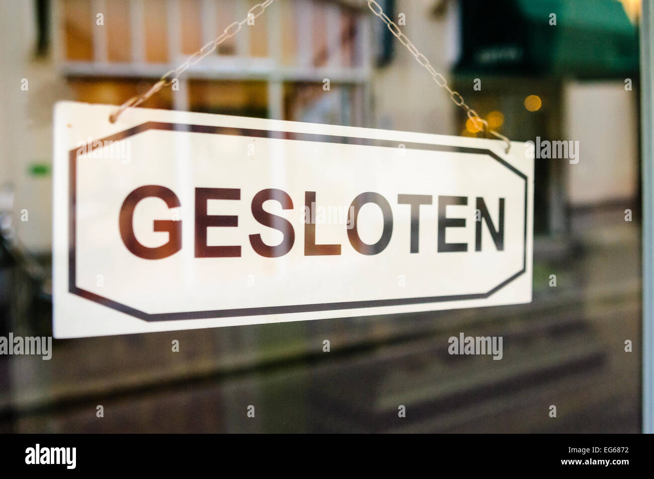 "Gesloten" (geschlossen) Schild an der Tür von einem holländischen Shop. Stockfoto