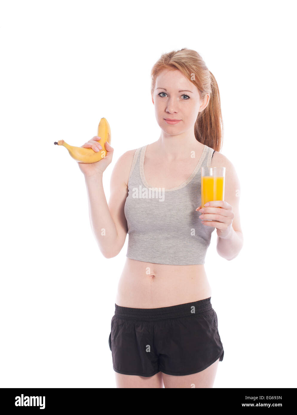 Sportliche Mädchen mit einer Banane und Saft in der Hand auf weißem Hintergrund. Stockfoto