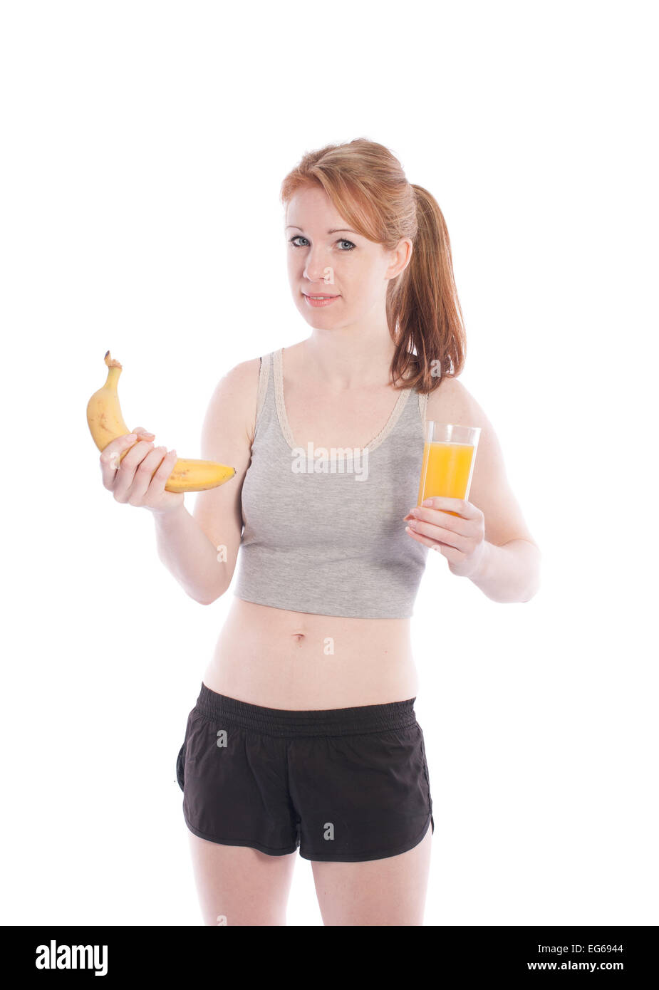 Sportliche Mädchen mit einer Banane und Saft in der Hand auf weißem Hintergrund. Stockfoto
