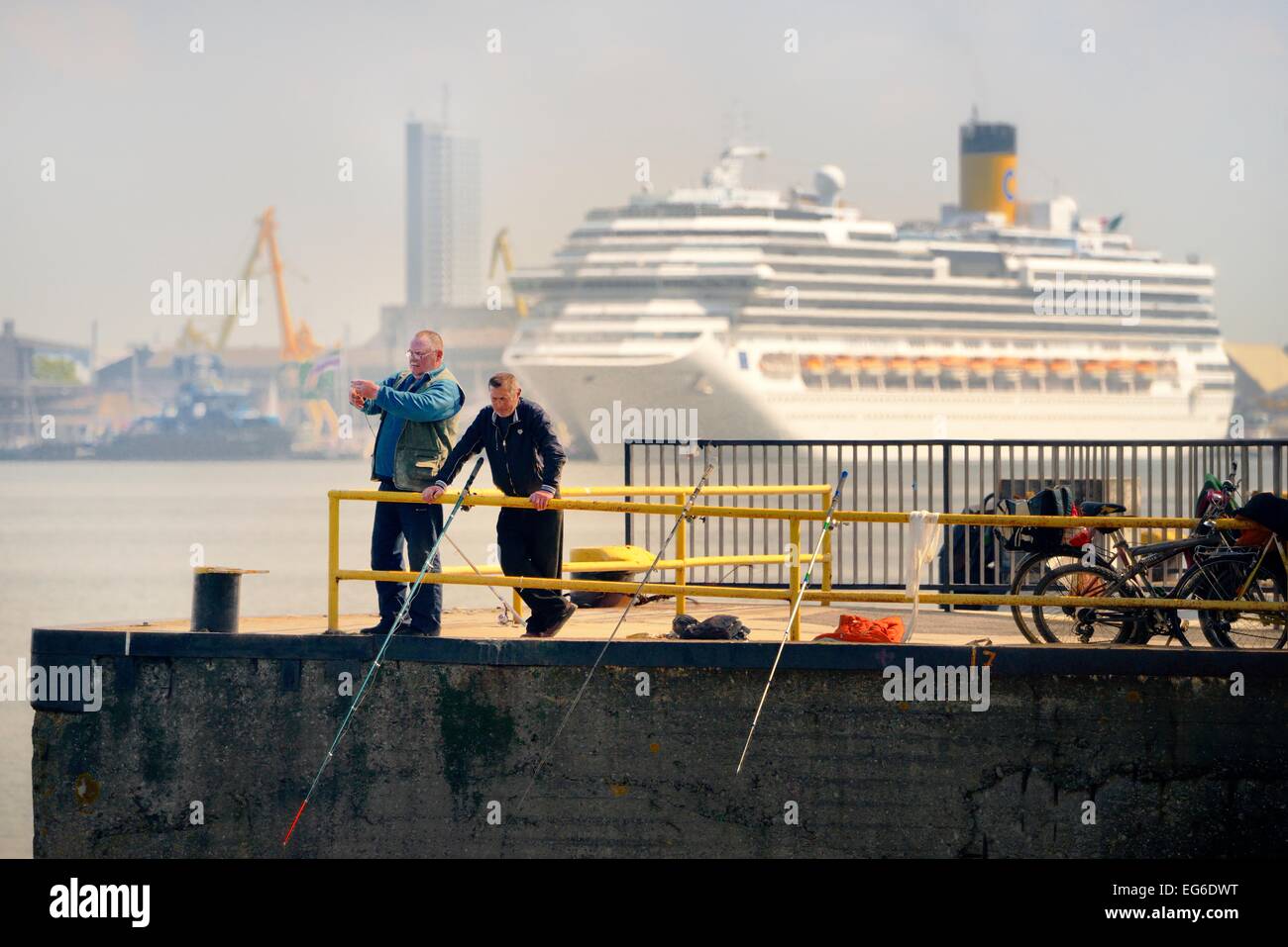 Klaipeda Litauen. Angeln von der Seebrücke entfernt. Kreuzfahrtschiff Costa Pacifica und Hafenanlagen in Fahrrinne in Zeitmessung Stockfoto