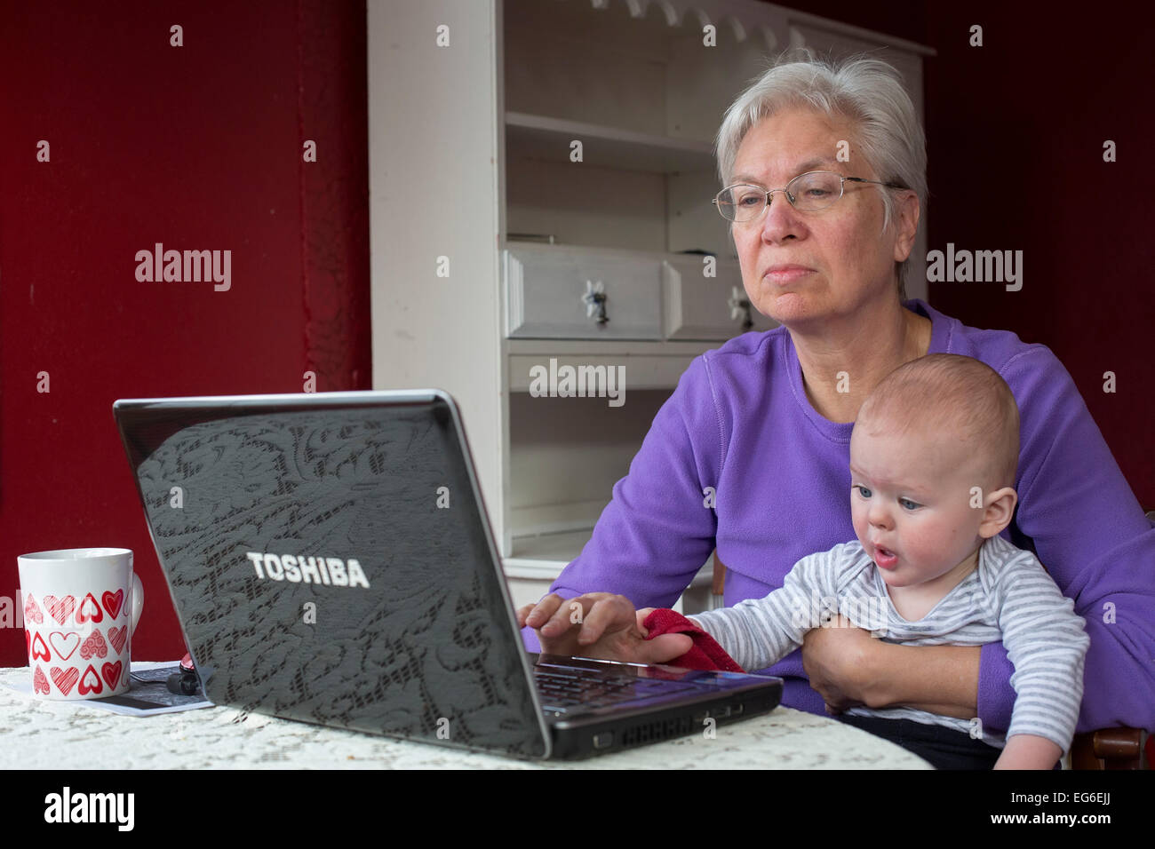 Denver, Colorado - sieben Monate alten Adam Hjermstad Jr. hilft seiner Großmutter, Susan Newell, 66, während sie an einem Computer arbeitet. Stockfoto