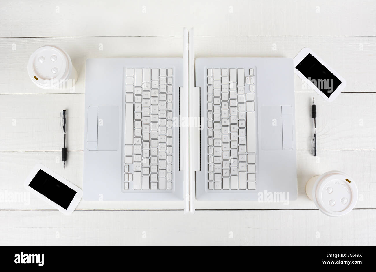 Hohen Winkel Schuss von zwei Laptop-Arbeitsplätze mit spiegelbildlich identische Layouts Rücken an Rücken. Querformat auf einem weißen Holz Stockfoto