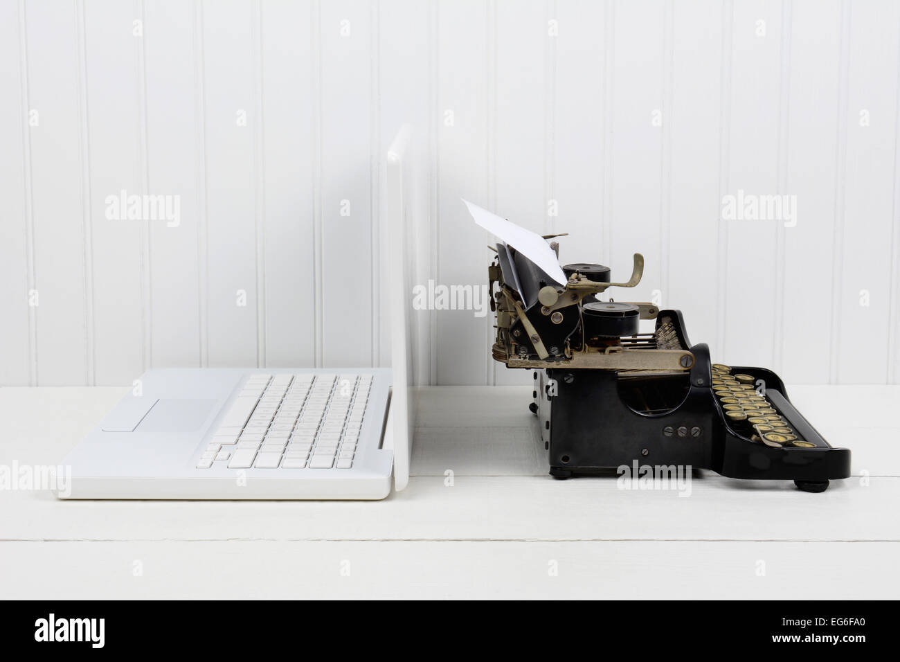 Nahaufnahme von einem weißen Schreibtisch mit einem modernen Laptop-Computer und eine antike Schreibmaschine Rücken an Rücken. Querformat mit Textfreiraum. Stockfoto