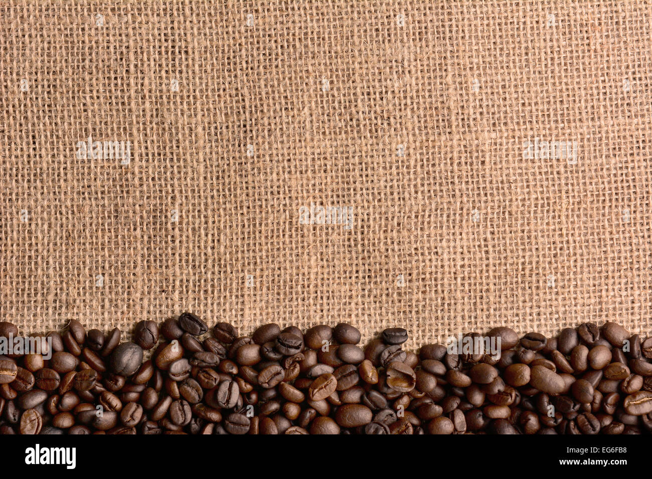 Hohen Winkel horizontale Schuss von frisch gerösteten Kaffeebohnen auf einer Leinwand-Oberfläche. Die Bohnen füllen die Unterseite des Rahmens, der Spitze ha Stockfoto