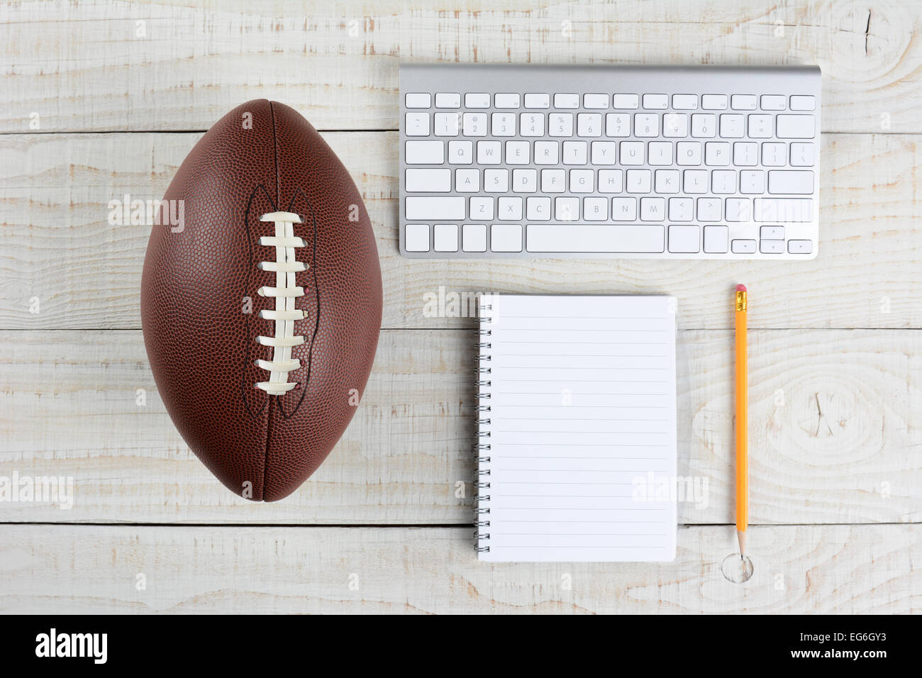 Fantasy Football Draft Stillleben. Eine Computer-Tastatur, Pad und Bleistift und ein amerikanischer Stil Fußball auf einen weißen Holztisch in eine Stockfoto