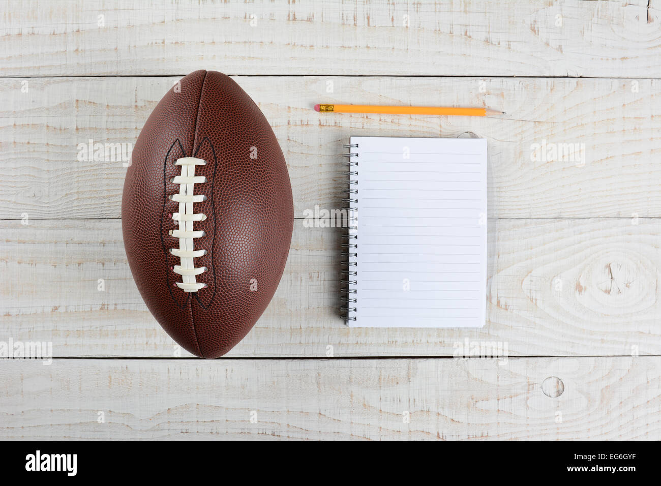 Fantasy Football Draft Stillleben. Ein Pad und Bleistift und ein amerikanisches Fußball auf einem weißen Holztisch im home Office. Stockfoto