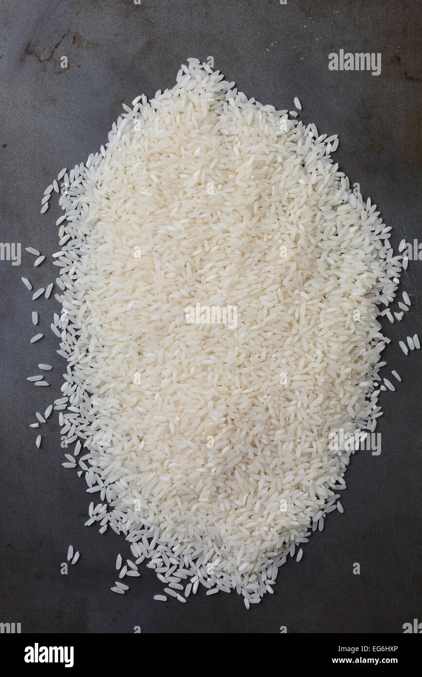 Hohen Winkel Schuss von einem Haufen von ungekochtem Reis Getreide auf einem Metall Backblech legen. Hochformat. Stockfoto