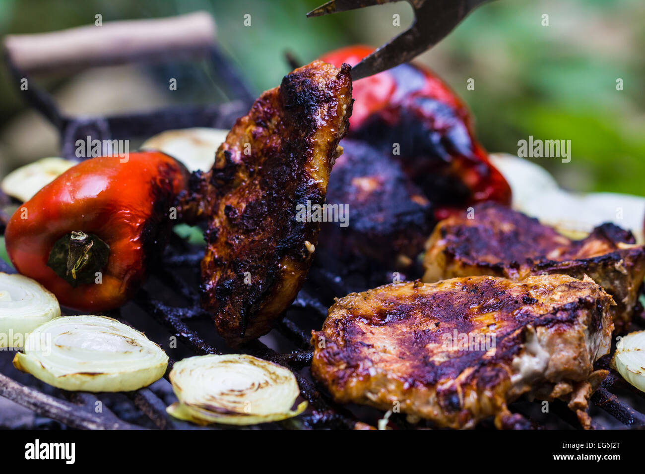 Steak, Wurst, Zwiebeln, Paprika und Toast auf einem Grill Stockfoto