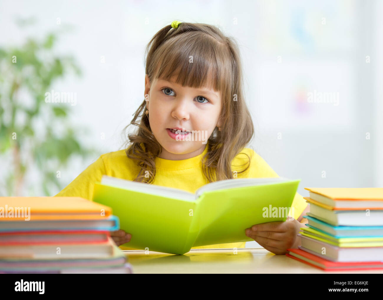 Niedliche kleine Mädchen lesen Geschichte aus großen Buch im Kindergarten Stockfoto