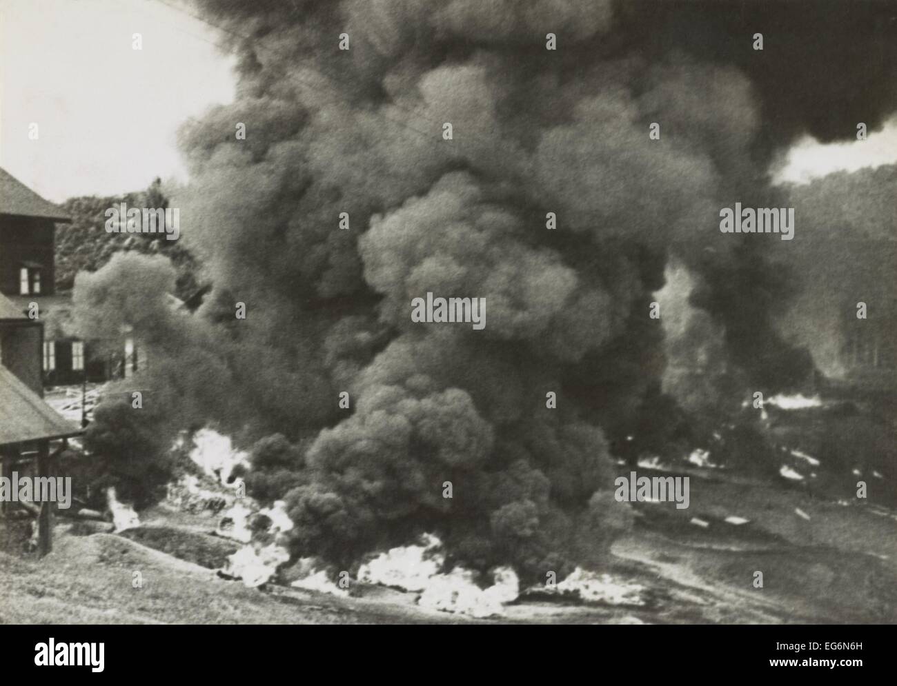 Rauch steigt aus einer Gummifabrik, zerstört von den sich zurückziehenden britischen Streitkräften in Malaya. Tausende von Ballen aus Kautschuk und Stockfoto