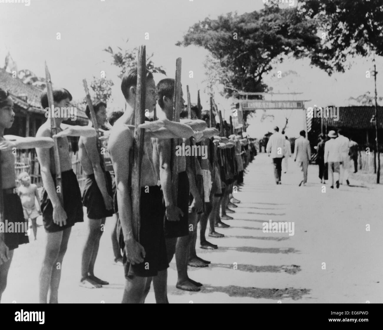 Barfuß Dorfbewohner führen Trainingsübungen mit Bambus-Gewehre bei einem französischen Legionär Außenposten. Batri, Französisch-Indochina, Stockfoto