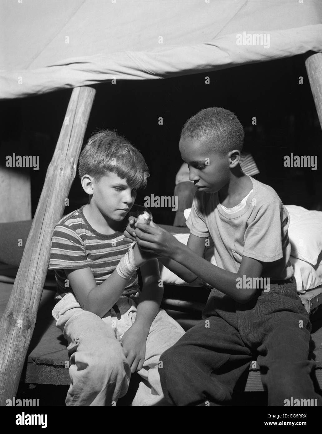 Afrikanische amerikanische Wohnmobil hilft eine weiße Bubby mit seiner bandagierte Hand. Sie sind im Camp Nathan Hale, Southfields, NY, das war Stockfoto