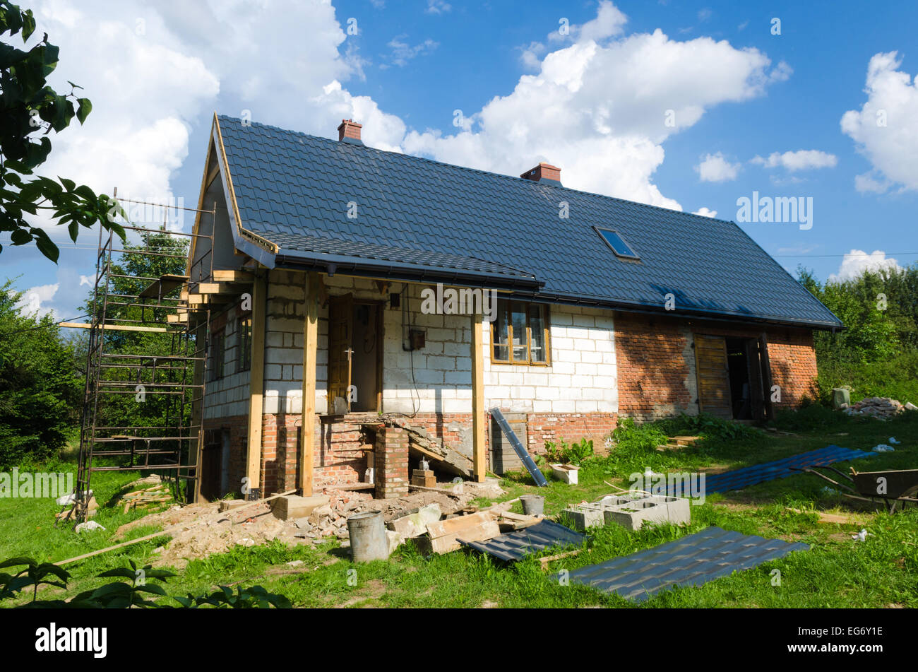 Ein Haus auf dem Lande wird renoviert und umgeben von Gerüste und Baumaterialien Stockfoto